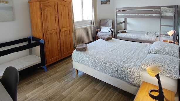 A bedroom with a wooden wardrobe, a single bed with patterned bedding, a chair, a desk, and a bedside table with a lamp. - Villa Laurier-Rose, Swimming pool, Petanque, 16 pers, Near lake, Ocean, Town center (Parentis-en-Born)