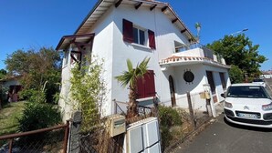 A two-story house with a white exterior, red shutters, and a small balcony. - Villa Laurier-Rose, Swimming pool, Petanque, 16 pers, Near lake, Ocean, Town center (Parentis-en-Born)