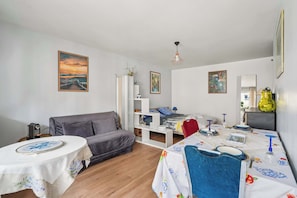 Una sala acogedora con un sofá, una mesa de comedor para dos personas y una cama al fondo.