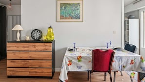 Een eethoek met een houten kast, een tafel met een bloemendecoratie en een rode stoel.