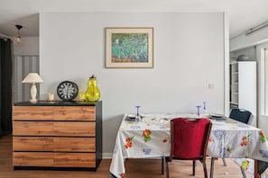 Un comedor con un armario de madera, una mesa con mantel floral y una silla roja.