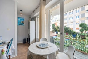 Un comedor con una mesa dispuesta para dos, un refrigerador blanco y un cartel en la pared.