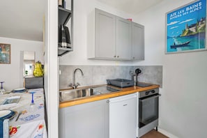 Una cocina compacta con un lavamanos, lavavajillas y horno pequeño. Cuenta con una encimera de madera y un cartel en la pared.