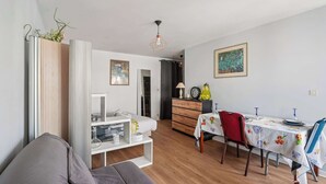 Een moderne, goed verlichte kamer met een bed, een eettafel met stoelen en een bank.
