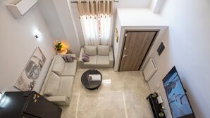 A modern living room with a sofa, a coffee table, and a TV. - Charming 2-bedroom house with WiFi, AC in fantastic Athina (Athina)