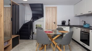 A compact kitchen with a dining area, a black spiral staircase, and a wooden door. - Charming 2-bedroom house with WiFi, AC in fantastic Athina (Athina)