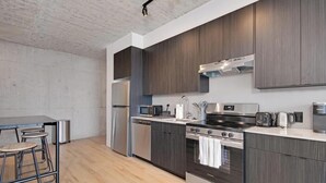 A modern kitchen with stainless steel appliances, wooden cabinets, and a bar area with stools.