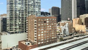 A cityscape with modern high-rise buildings, a train track, and a parking area.
