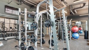 A gym with weightlifting equipment, dumbbells, and exercise balls.