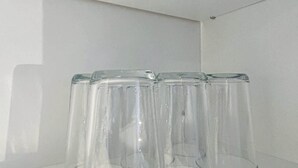 A row of clear glass tumblers on a white shelf against a white wall. - South Loop Rooftop With In and Out Parking 2 (Chicago)