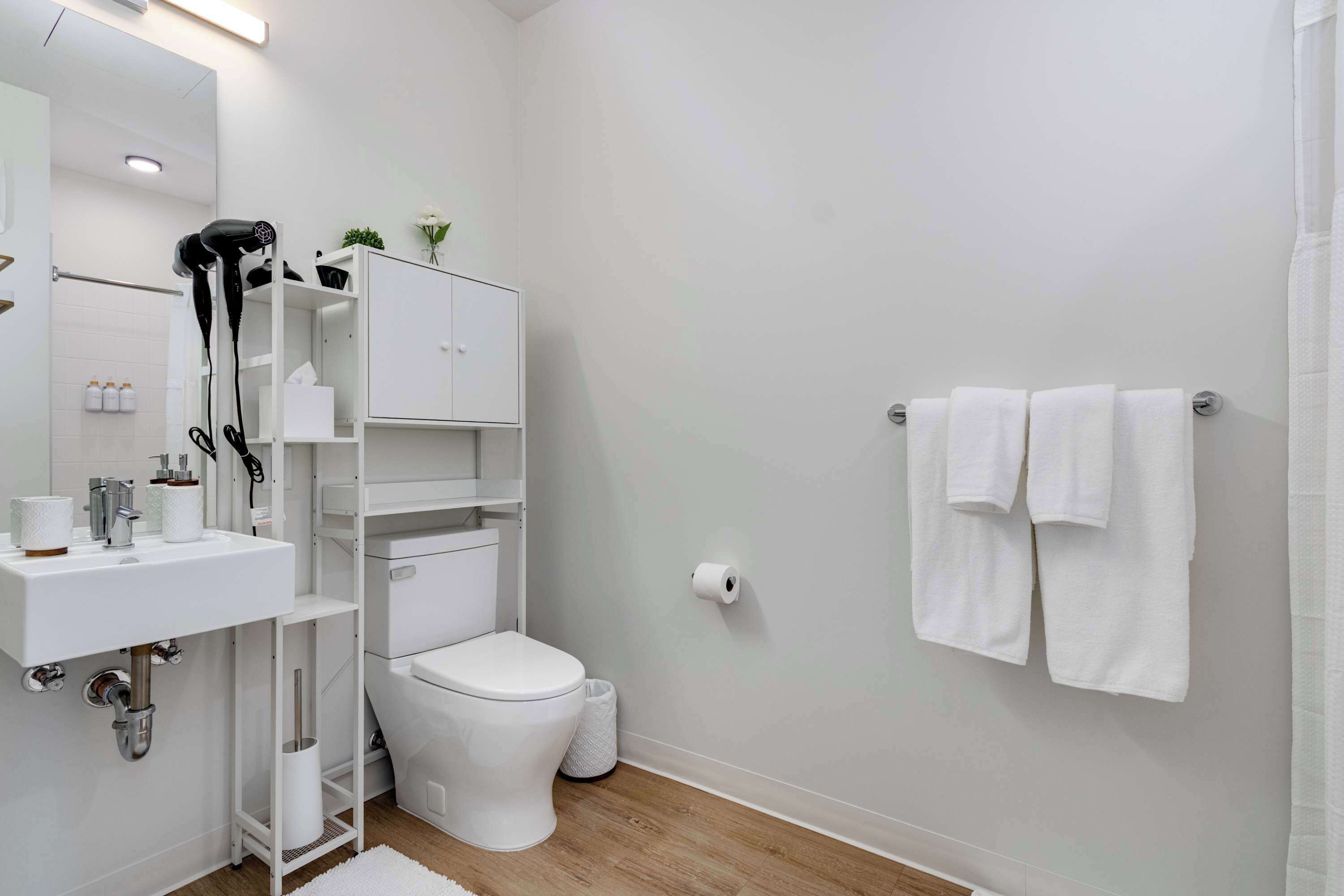 Une salle de bain moderne avec un lavabo, des toilettes et un porte-serviettes, le tout de couleur blanche.