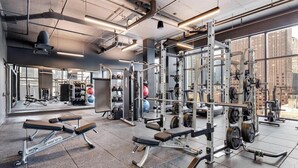 A gym with weightlifting equipment, benches, and a mirrored wall. - South Loop Rooftop With In and Out Parking 3 (Chicago)