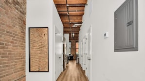 A hallway with exposed brick walls, wooden flooring, and white doors. - River North Rooftop With In and Out Parking 1 (Chicago)