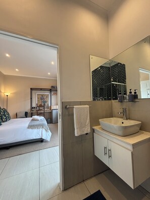 Un baño moderno con un espejo grande, un lavabo blanco y una toalla colgada en un perchero.