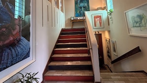Una escalera con peldaños rojos, un tapete de cuero de vaca y cuadros en las paredes.