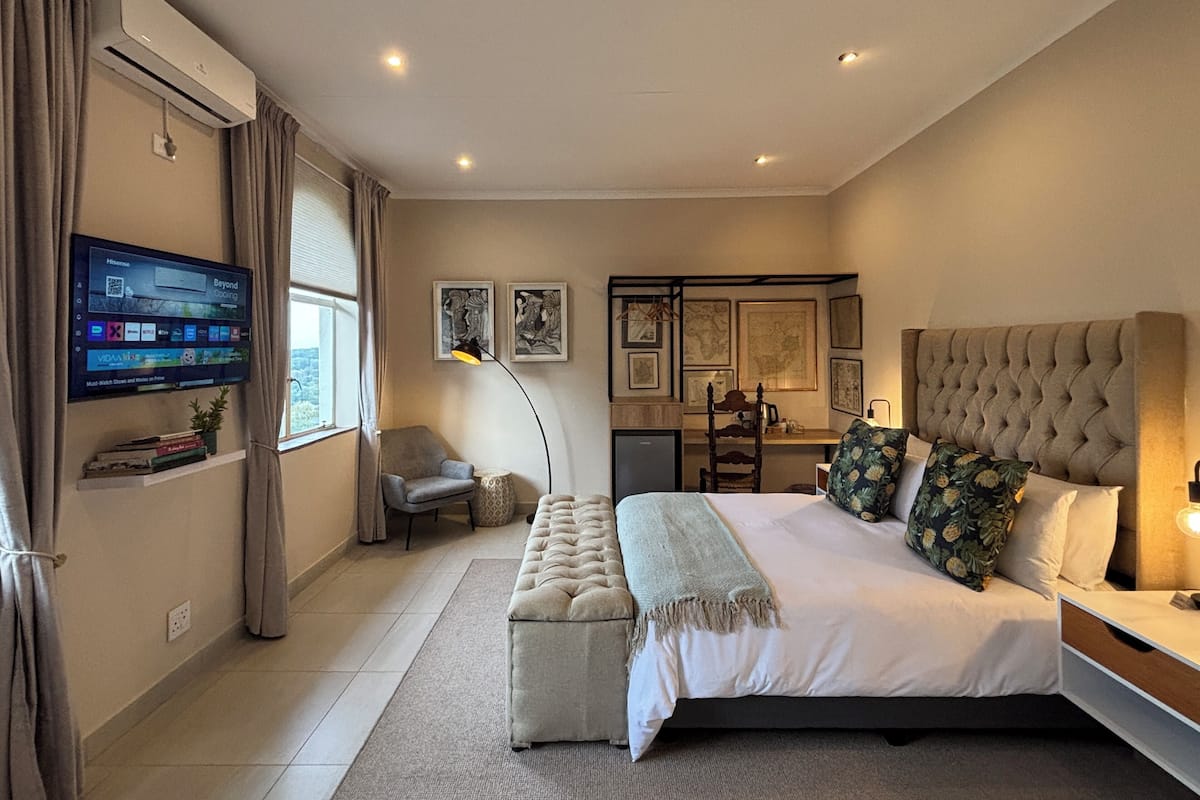 Un dormitorio moderno con una cama grande, un escritorio y un televisor montado en la pared.