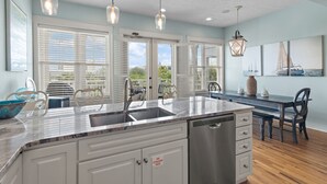 A kitchen with a large island, white cabinetry, and a stainless steel dishwasher.