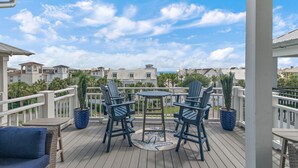 A covered outdoor area with a table and chairs, a potted plant, and a view of neighboring buildings.