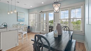 A kitchen with a wooden island, white cabinetry, and a dining area with a dark wooden table and chairs.