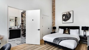 A modern bedroom with a large bed, a black headboard, and a white door leading to a bathroom. - River North Rooftop With In and Out Parking 6 (Chicago)