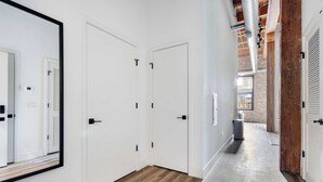 A hallway with white doors, a wooden floor, and a view into a kitchen area. - River North Rooftop With In and Out Parking 6 (Chicago)