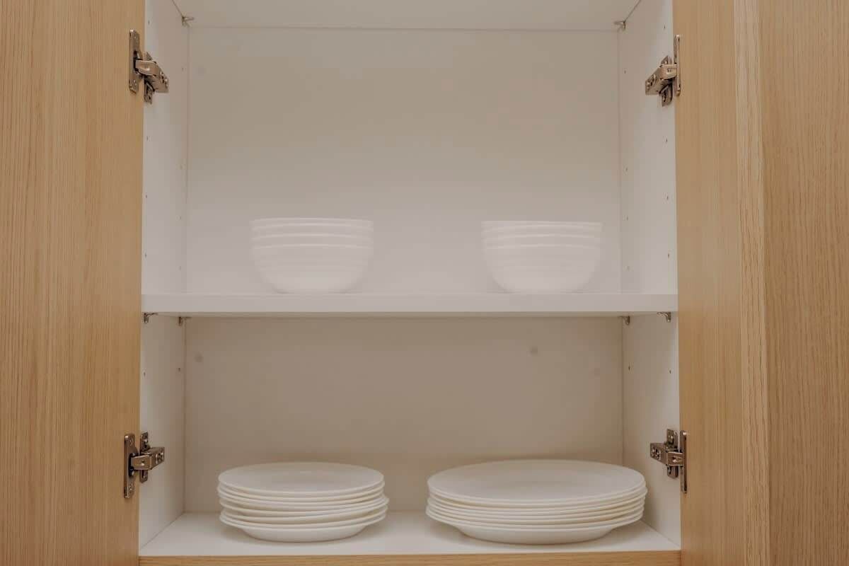A cabinet with two shelves; the top shelf holds two bowls, and the bottom shelf holds two stacks of plates.
