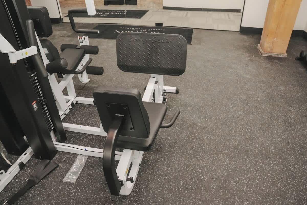 Een fitnessruimte met diverse trainingsapparaten, waaronder een bank en krachttoestellen.