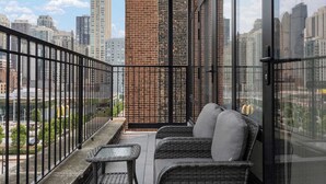 A balcony with a wicker sofa and table, a brick wall, and a city view. - River North Private Deck With In and Out Parking (Chicago)