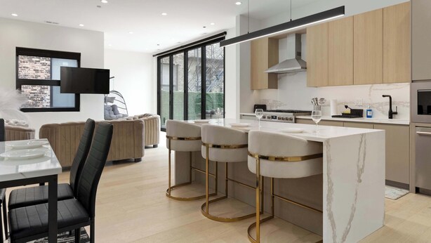 A modern kitchen with a central island, bar stools, and a dining table. - River North Private Deck With In and Out Parking (Chicago)