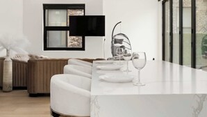 A modern living room with a white sofa, a glass coffee table, and a TV mounted on the wall. - River North Private Deck With In and Out Parking (Chicago)
