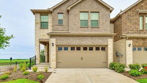 A two-story house with a beige garage door, stone facade, and a small front porch.