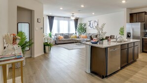 A modern kitchen with a central island, a dining area with a sofa, and a living room with a sofa and a coffee table.