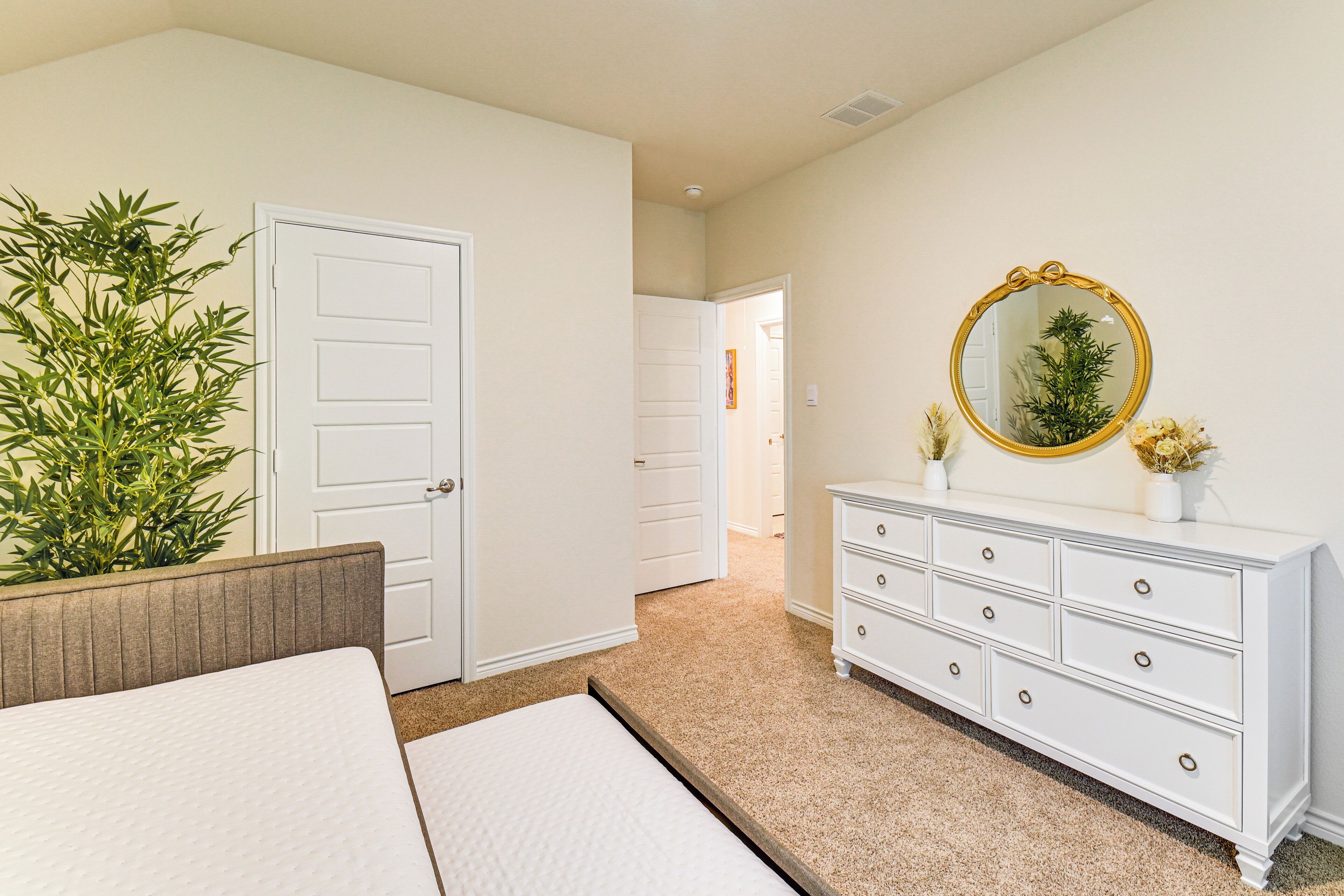 Un dormitorio con cama, cómoda, espejo y puerta.