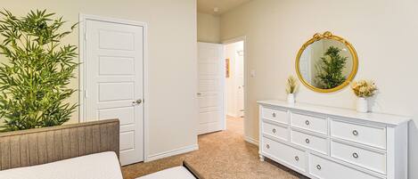 Un dormitorio con cama, cómoda, espejo y puerta.
