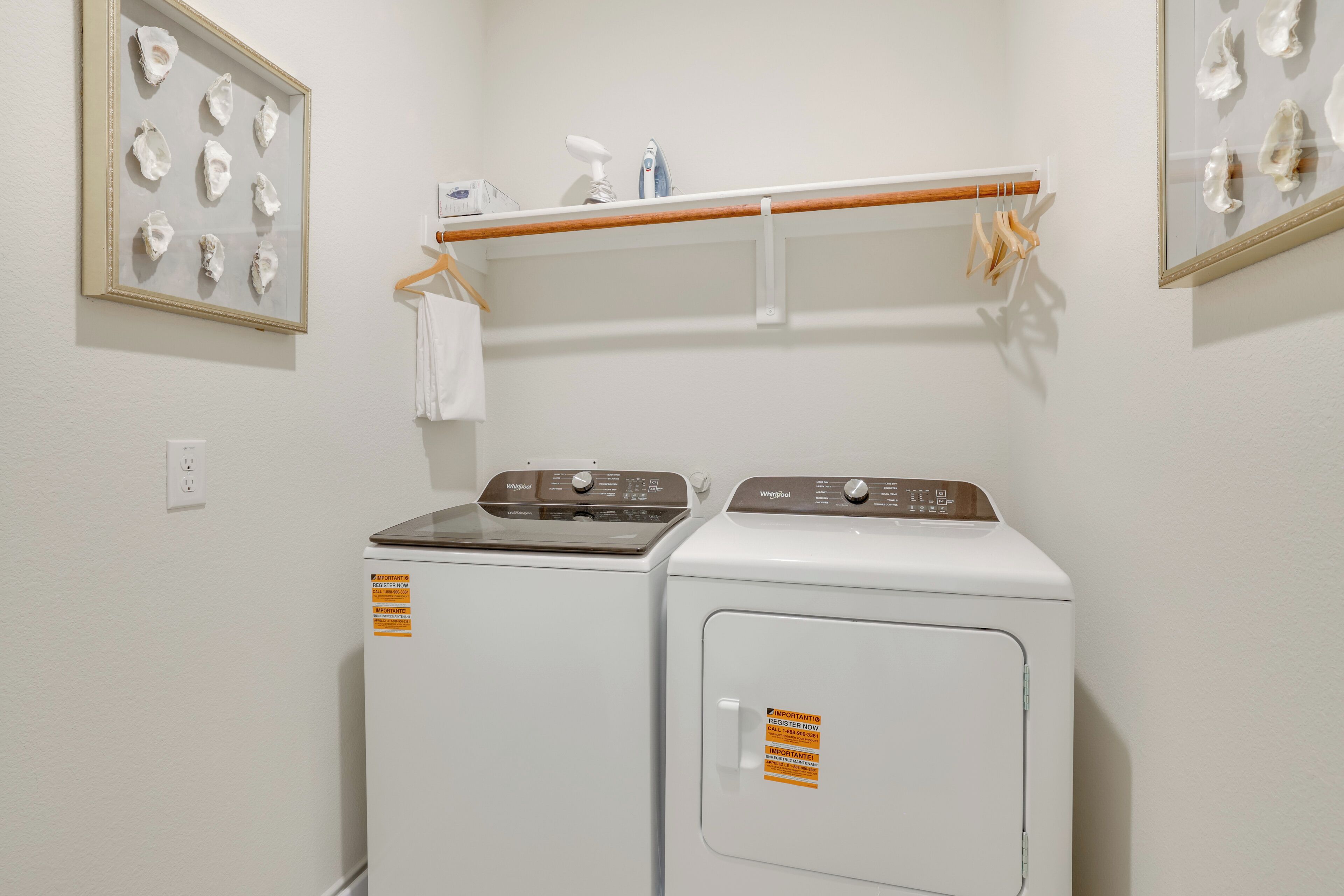 Une buanderie équipée de deux machines à laver à chargement frontal, d’un étendoir et de tableaux encadrés accrochés aux murs.