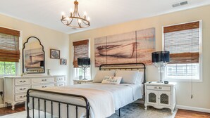Een slaapkamer met een bed, dressoir, nachtkastje en kunstwerken aan de wand.