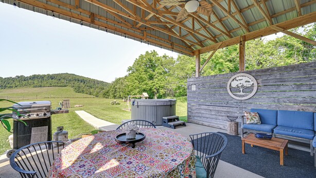 An outdoor patio with a covered seating area, a grill, and a decorative wall.