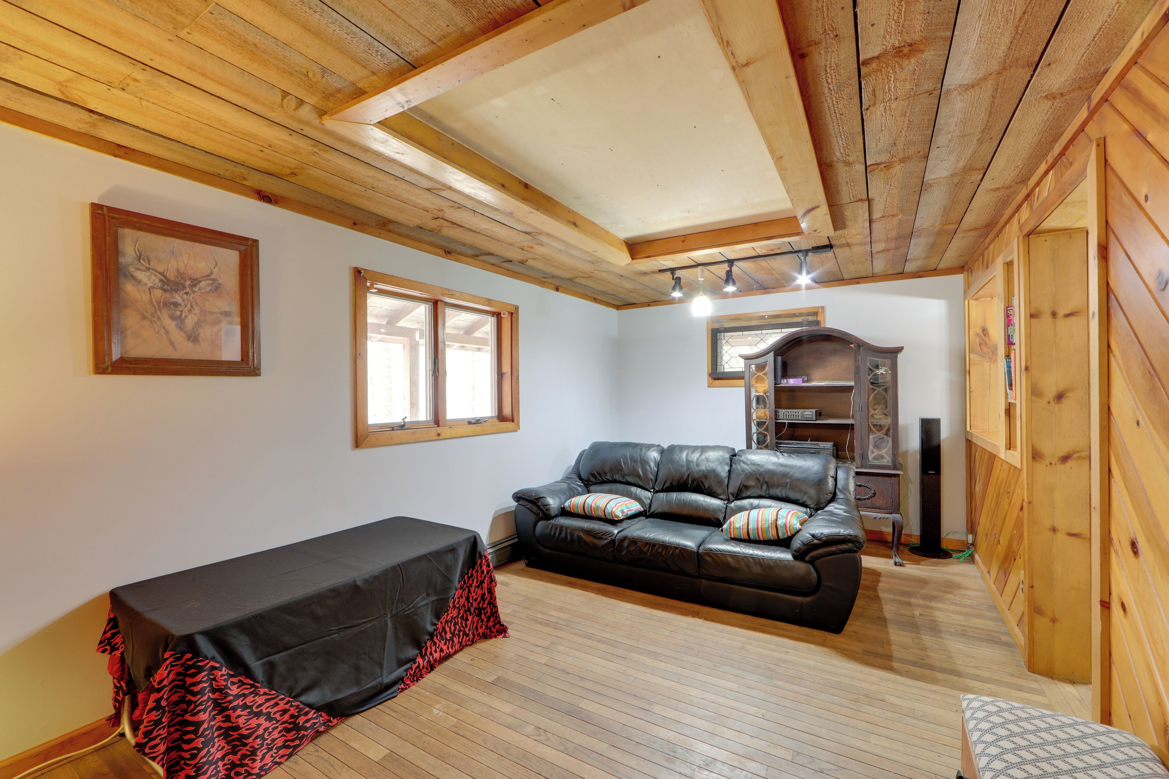 Una sala de estar acogedora con un sofá de cuero, una mesita con mantel negro y paredes de madera.