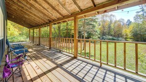Un patio in legno coperto con ringhiera, una sedia pieghevole blu e una sedia pieghevole viola.
