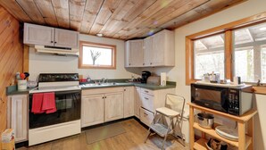 Una cucina con mobili in legno, un fornello, un forno a microonde e una finestra.