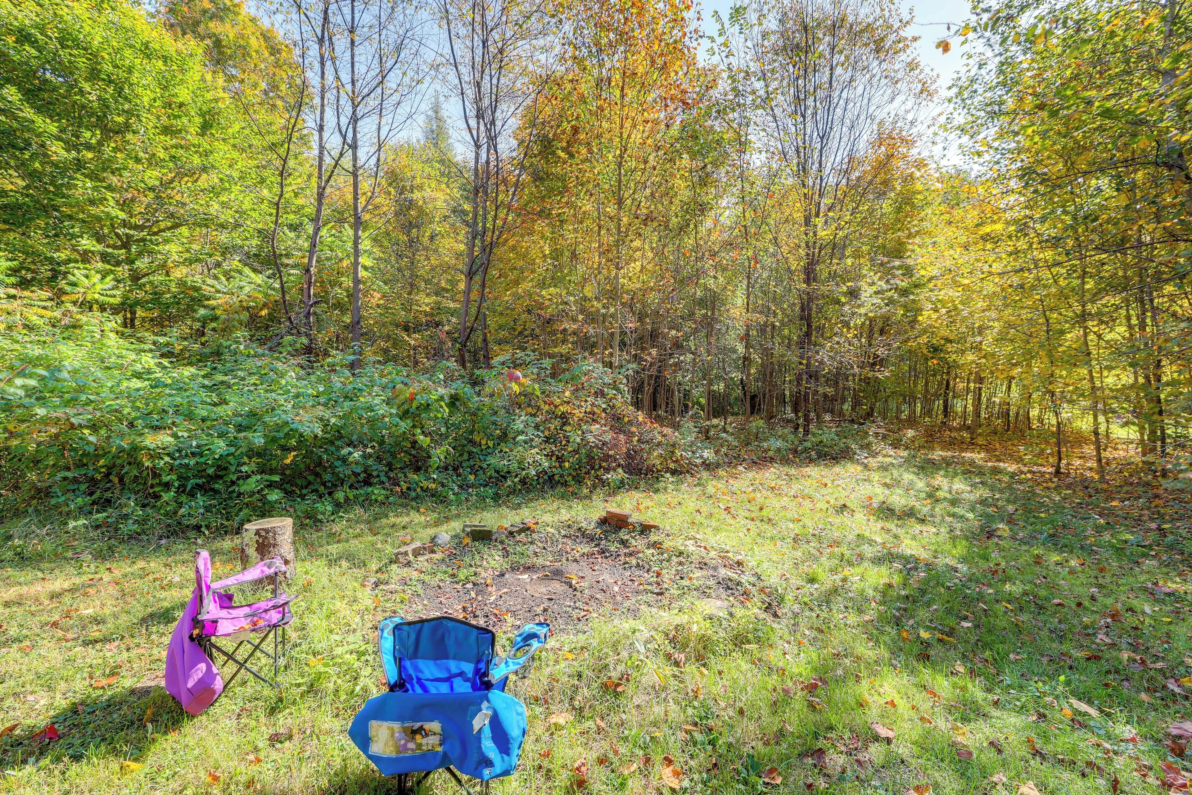 A forest clearing with two camping chairs and a backpack.
