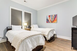 Une chambre avec deux lits, une table de chevet, une lampe et un meuble pour la télévision.
