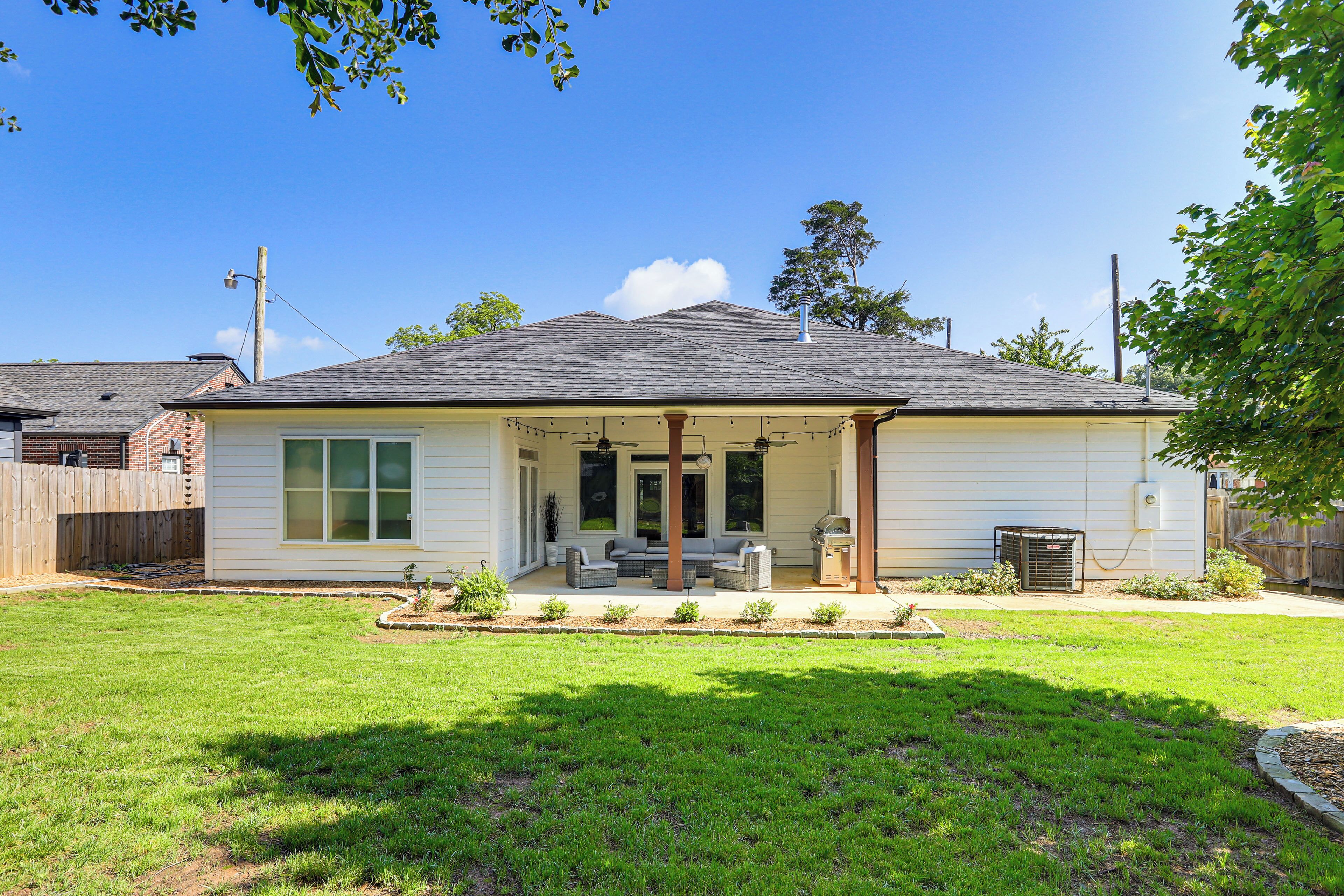 A single-story house with a covered patio, a lawn, and a wooden fence.