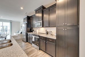 A modern kitchen with dark cabinetry, stainless steel appliances, and a granite countertop. - 2 Mi to Uptown Charlotte: Family Townhome! (Charlotte)