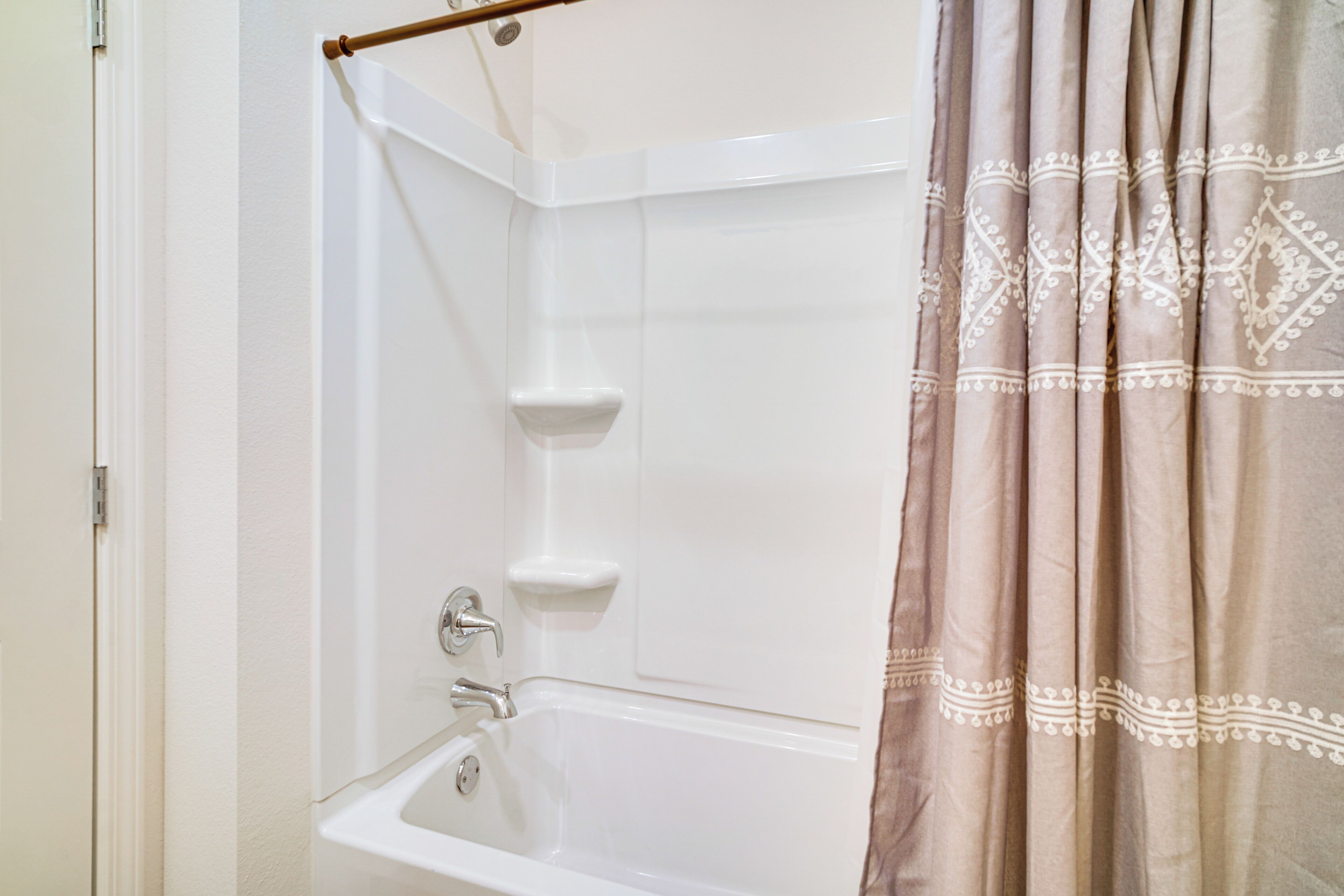 A bathroom with a white bathtub, a shower curtain, and a towel rack.