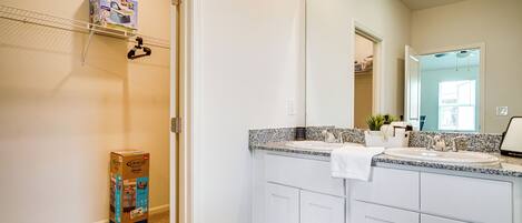 A bathroom with a white vanity, a large mirror, and a box of Graco Premium Plus carpet cleaner on the floor.