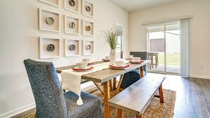 A dining area with a wooden table, blue upholstered chairs, and a white vase with a plant. - 12 Mi to Avery Island: Spacious Family Home! (New Iberia)