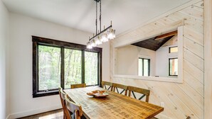 Un espace repas comprenant une table en bois, des chaises et un luminaire suspendu.