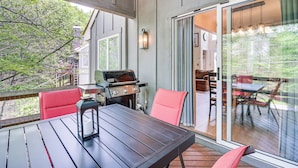 A covered patio with a table and chairs, a grill, and a view of the outdoors.