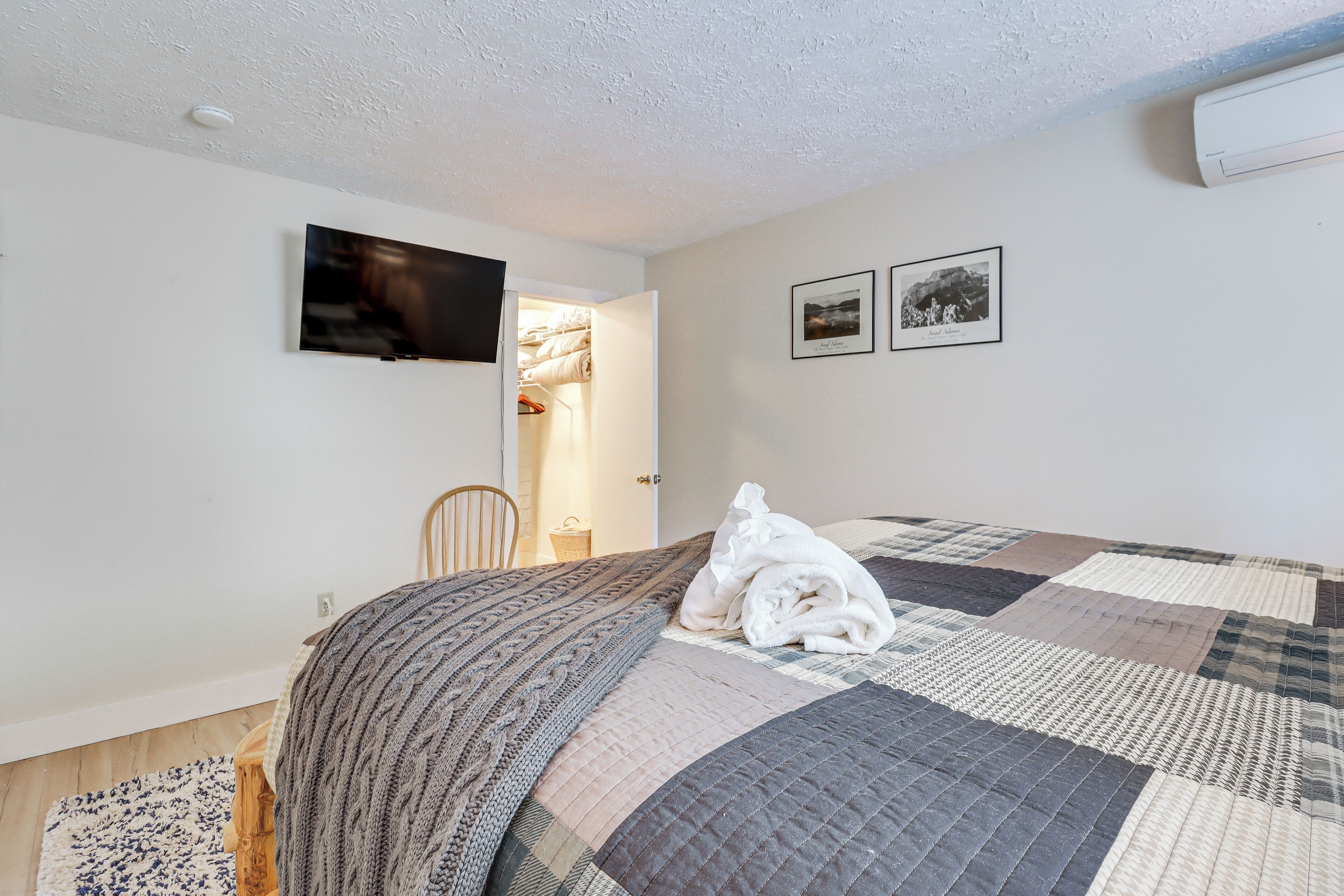 Un dormitorio con una cama, un televisor y dos cuadros en la pared.